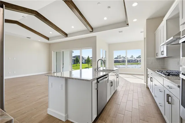 a large kitchen with stainless steel appliances granite countertop a lot of counter space and a wooden floors