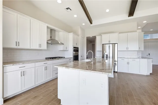 a kitchen with stainless steel appliances granite countertop a refrigerator a sink dishwasher a stove and white cabinets with wooden floor