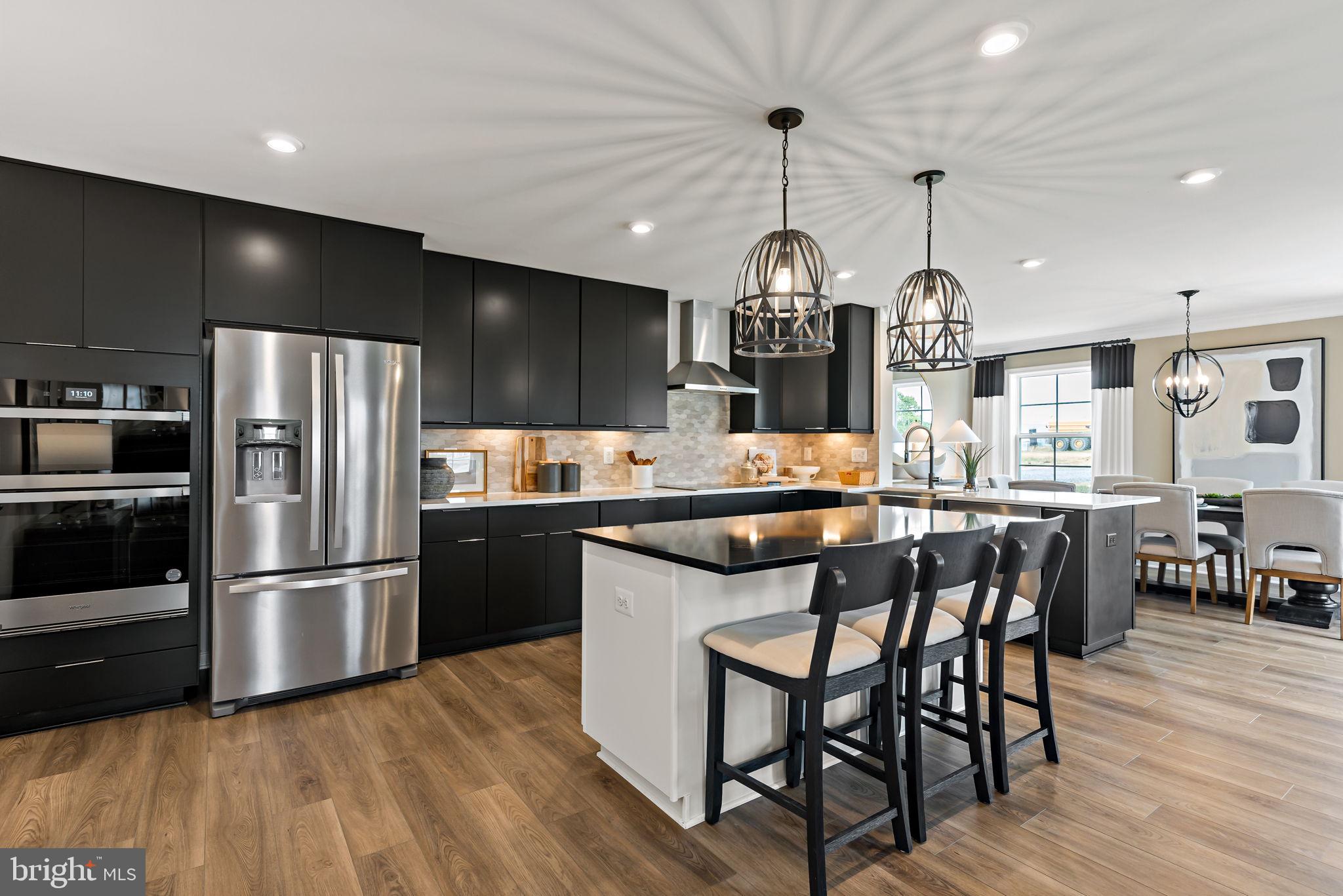Tbb Tbb Outrigger Road, Unit CARNEGIE Inwood, WV 25428 - Photo 7 of 60 a kitchen with stainless steel appliances kitchen island granite countertop a table chairs and wooden floor