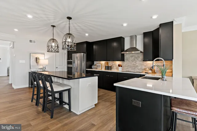 a kitchen with stainless steel appliances kitchen island granite countertop a sink a stove a refrigerator and island with wooden floor