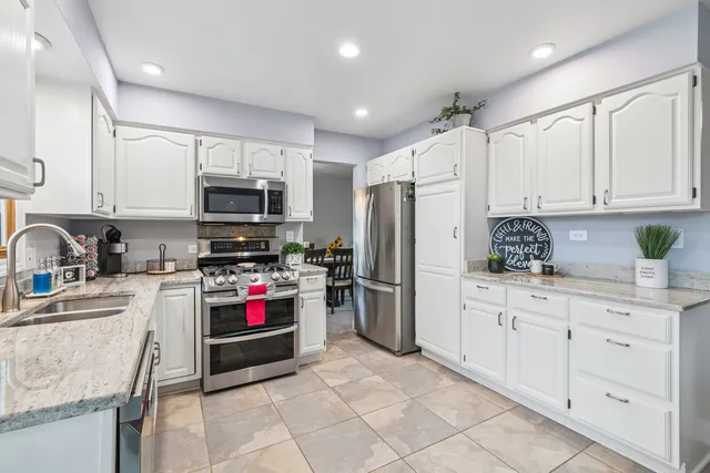 a kitchen with stainless steel appliances granite countertop a refrigerator sink and stove