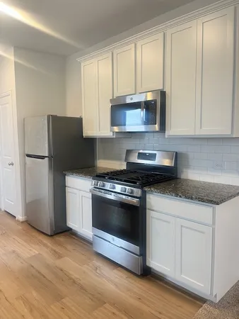 a kitchen with granite countertop white cabinets and white appliances