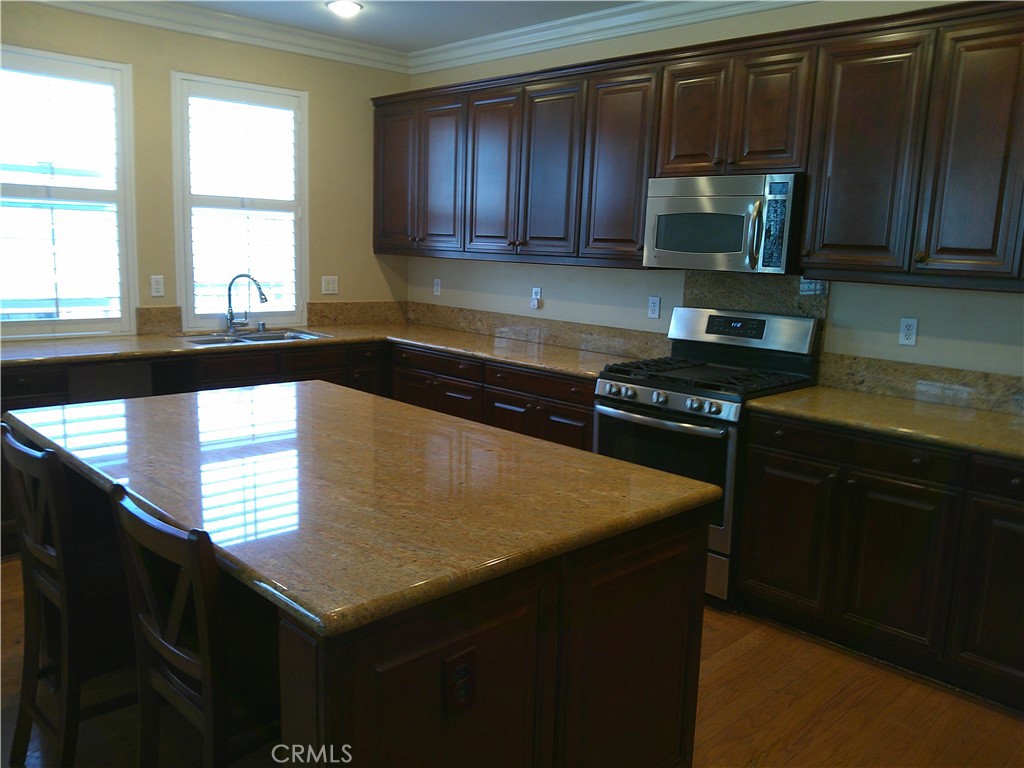 14 Durlston Way Ladera Ranch, CA 92694 - Photo 27 of 38 a kitchen with stainless steel appliances a sink dishwasher stove microwave and cabinets