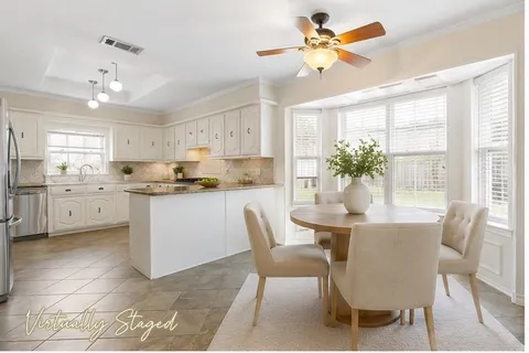 a kitchen with a dining table chairs cabinets and stainless steel appliances