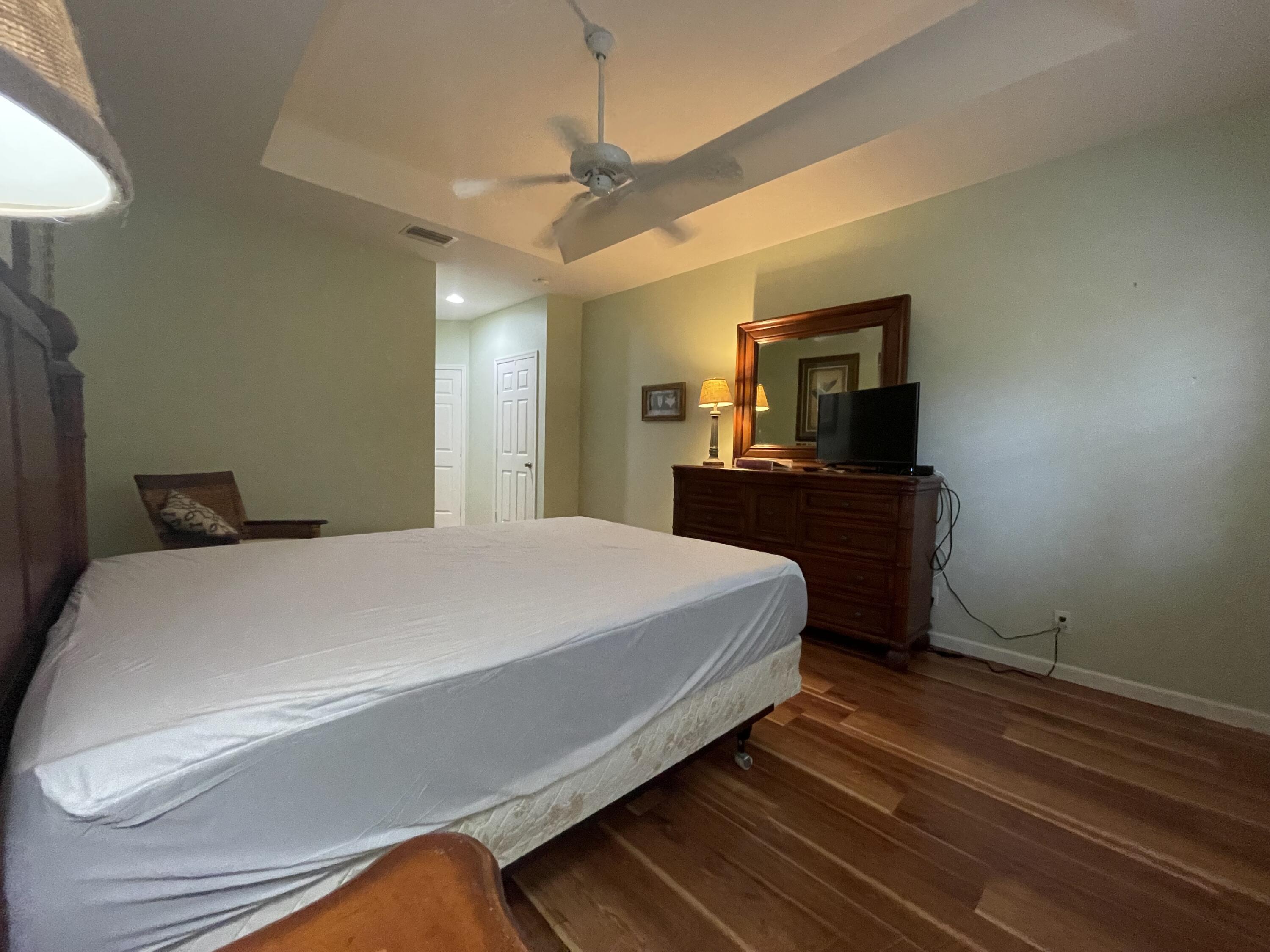 9125 Sand Shot Way, Unit A Port St. Lucie, FL 34986 - Photo 13 of 22 a bedroom with a bed and a flat tv screen on dresser