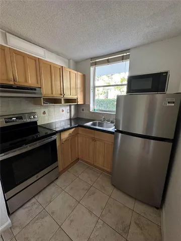 a kitchen with a refrigerator sink and cabinets