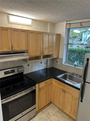a kitchen with granite countertop a sink stove and cabinets