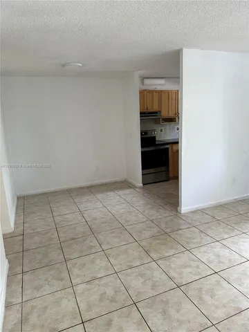 a view of an empty room and kitchen