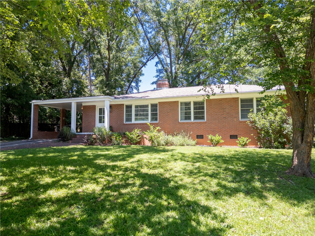 207 Brook Street Clemson, SC 29631 - Photo 29 of 39 Mature trees frame this classic brick facade, offering a welcoming, verdant curb appeal.
