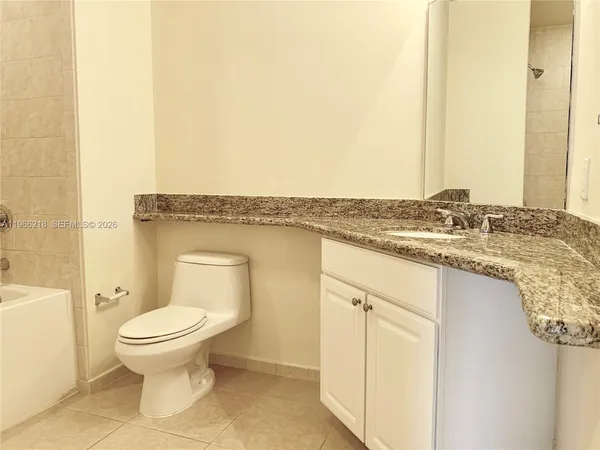 a bathroom with a granite countertop toilet sink and mirror