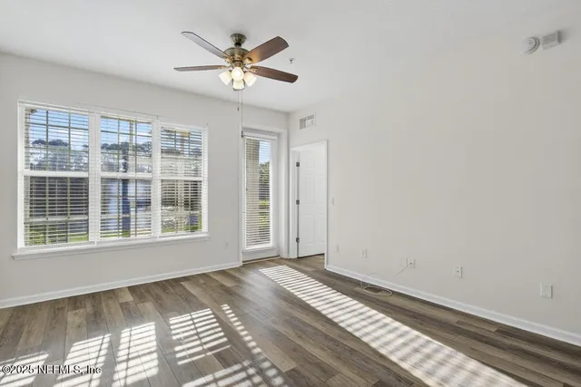 a view of a bedroom with wooden floor and a ceiling fan