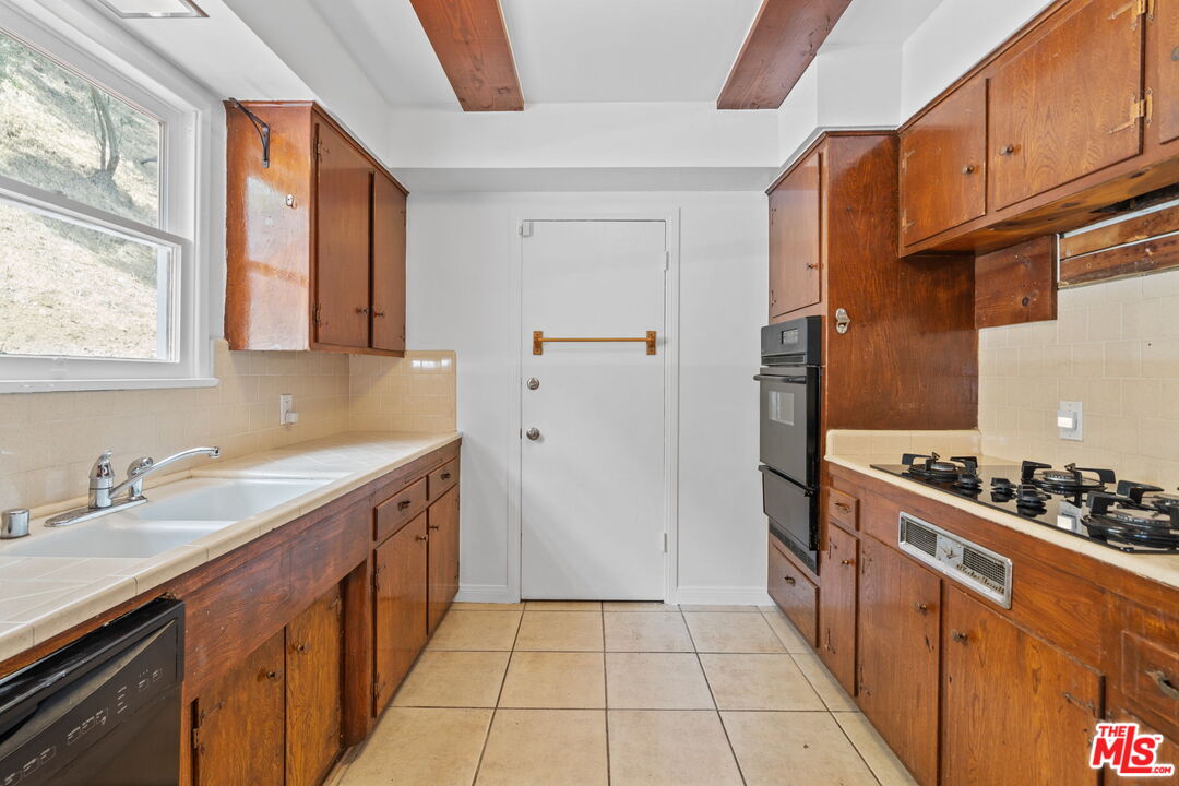 2485 Benedict Canyon Drive Beverly Hills, CA 90210 - Photo 11 of 33 a kitchen with stainless steel appliances a sink stove and refrigerator