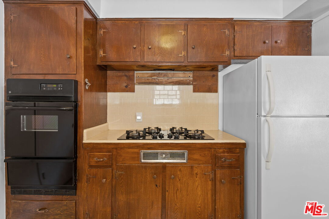 2485 Benedict Canyon Drive Beverly Hills, CA 90210 - Photo 13 of 33 a kitchen with stainless steel appliances granite countertop a refrigerator and a stove