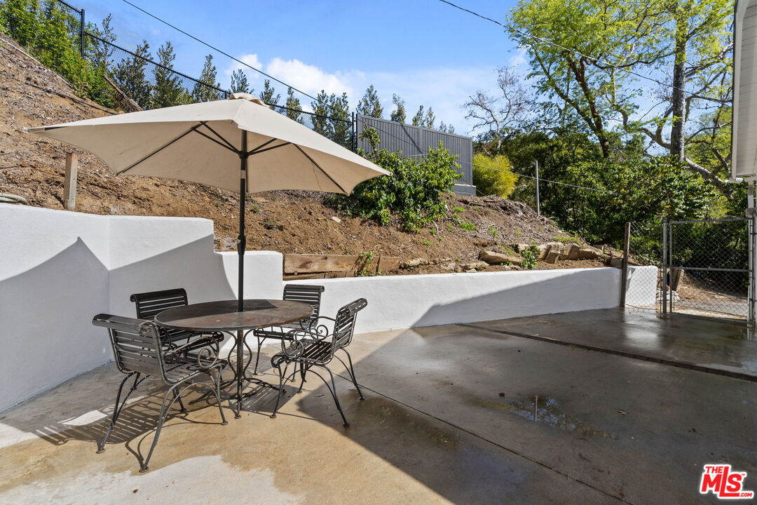 2485 Benedict Canyon Drive Beverly Hills, CA 90210 - Photo 26 of 33 a view of a patio with table and chairs under an umbrella