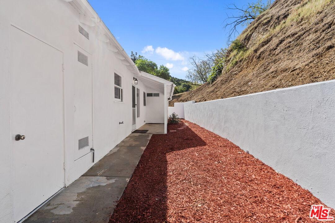 2485 Benedict Canyon Drive Beverly Hills, CA 90210 - Photo 27 of 33 a front view of a house with a yard