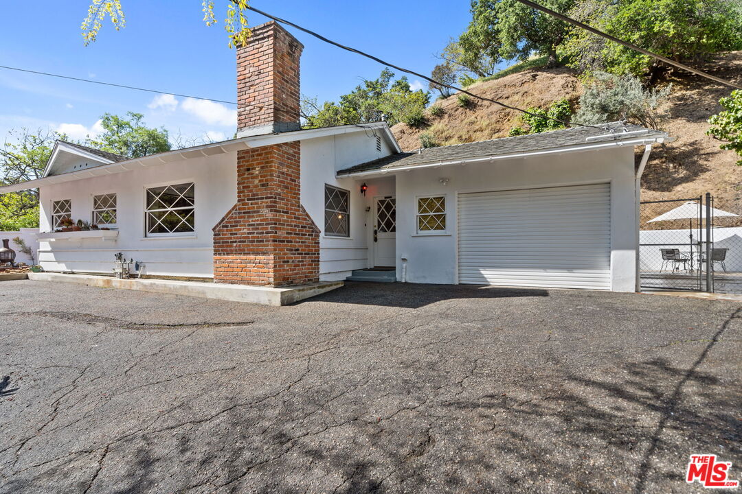 2485 Benedict Canyon Drive Beverly Hills, CA 90210 - Photo 3 of 33 a view of a house with a yard and garage