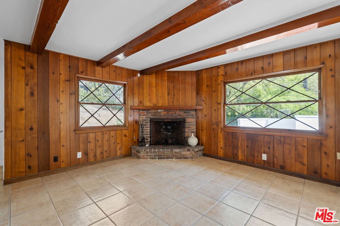 2485 Benedict Canyon Drive Beverly Hills, CA 90210 - Photo 7 of 33 a view of an empty room with a fireplace and a window