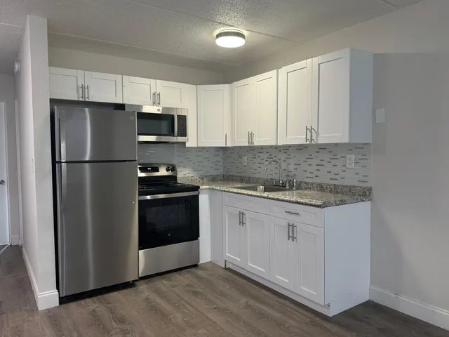 a kitchen with granite countertop white cabinets and stainless steel appliances