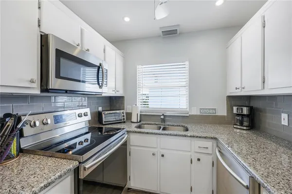 a kitchen with stainless steel appliances granite countertop a sink stove and microwave