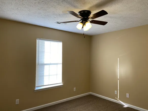 an empty room with a window and a fan