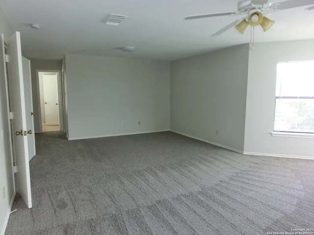 an empty room with wooden floor fan and windows