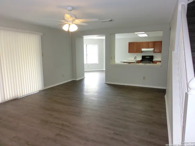 a view of an empty room with kitchen and window