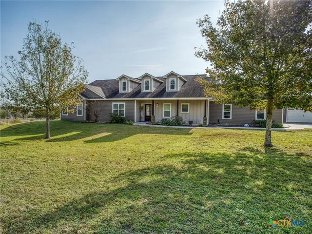 a view of a house with a big yard and large trees
