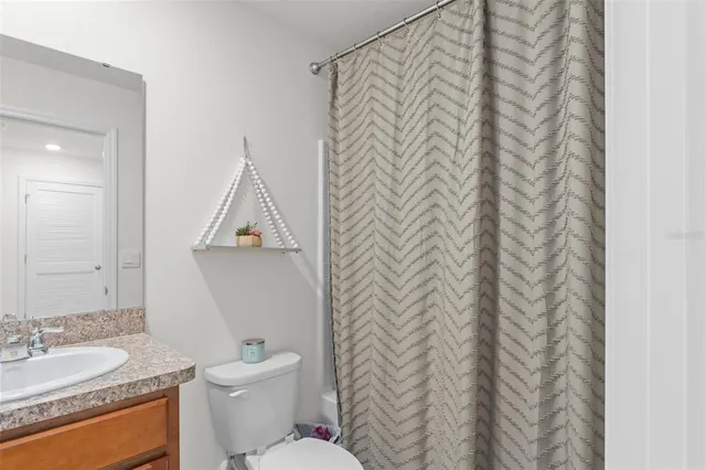 a bathroom with a granite countertop sink and a toilet