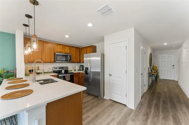 a kitchen with a refrigerator a sink and wooden floor