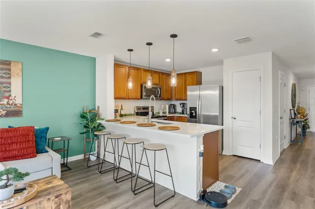 a kitchen with kitchen island a stove a refrigerator a dining table and chairs with wooden floor