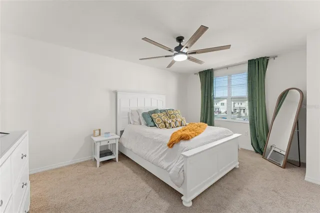 a bedroom with a bed a dresser and a large window