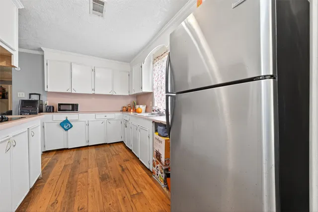 a kitchen with sink a refrigerator and white cabinets