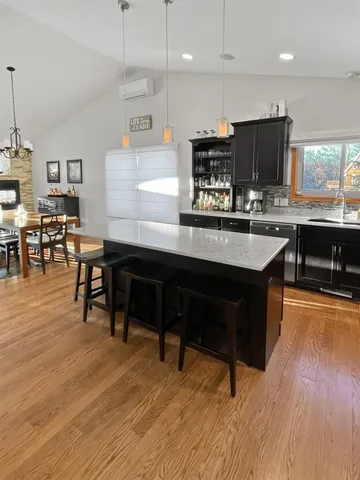 a large kitchen with kitchen island a stove a sink a refrigerator and a dining table with wooden floor
