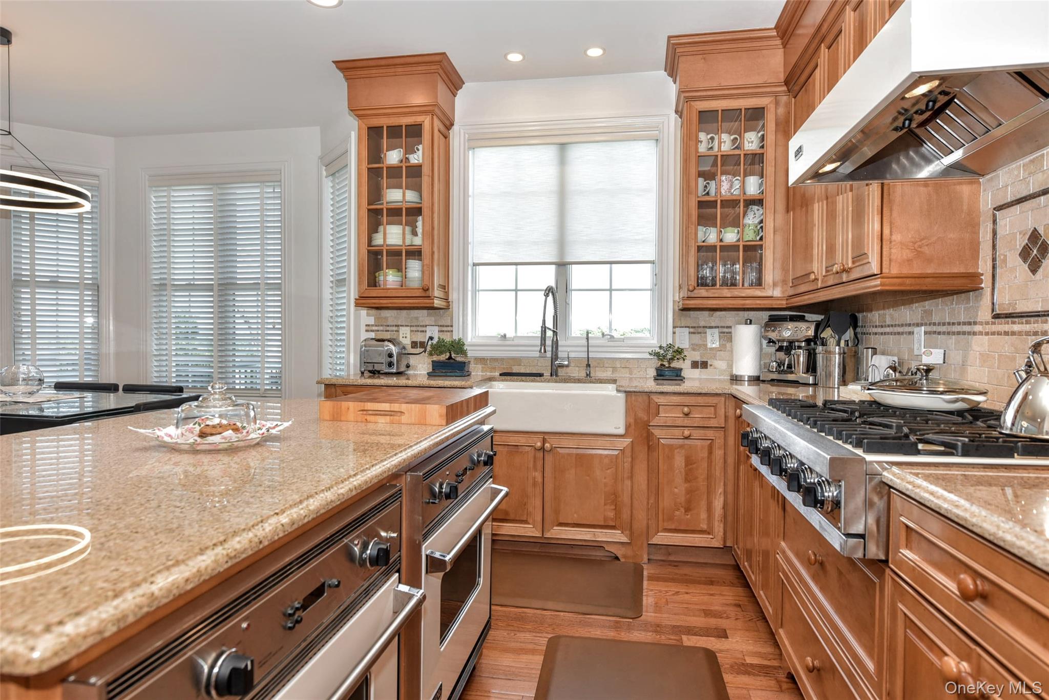 46 Mansion Ridge Boulevard Monroe, NY 10950 - Photo 17 of 46 Gourmet kitchen featuring a large central island with integrated oven, a built-in range with an overhead exhaust hood, wood-finish cabinetry, a farmhouse sink, and polished countertops