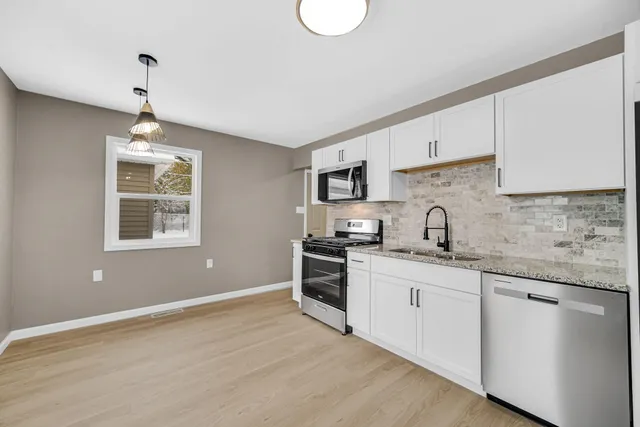 a kitchen with stainless steel appliances granite countertop a sink a stove a refrigerator and window