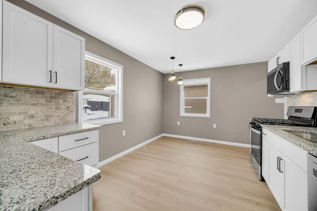 a kitchen with granite countertop a stove a sink and a microwave