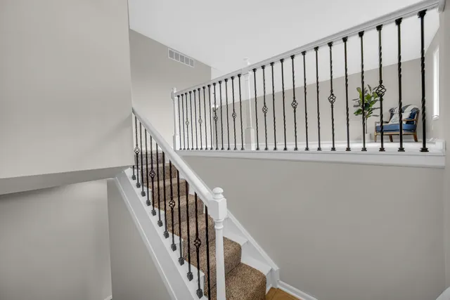 a view of staircase with railing and white walls