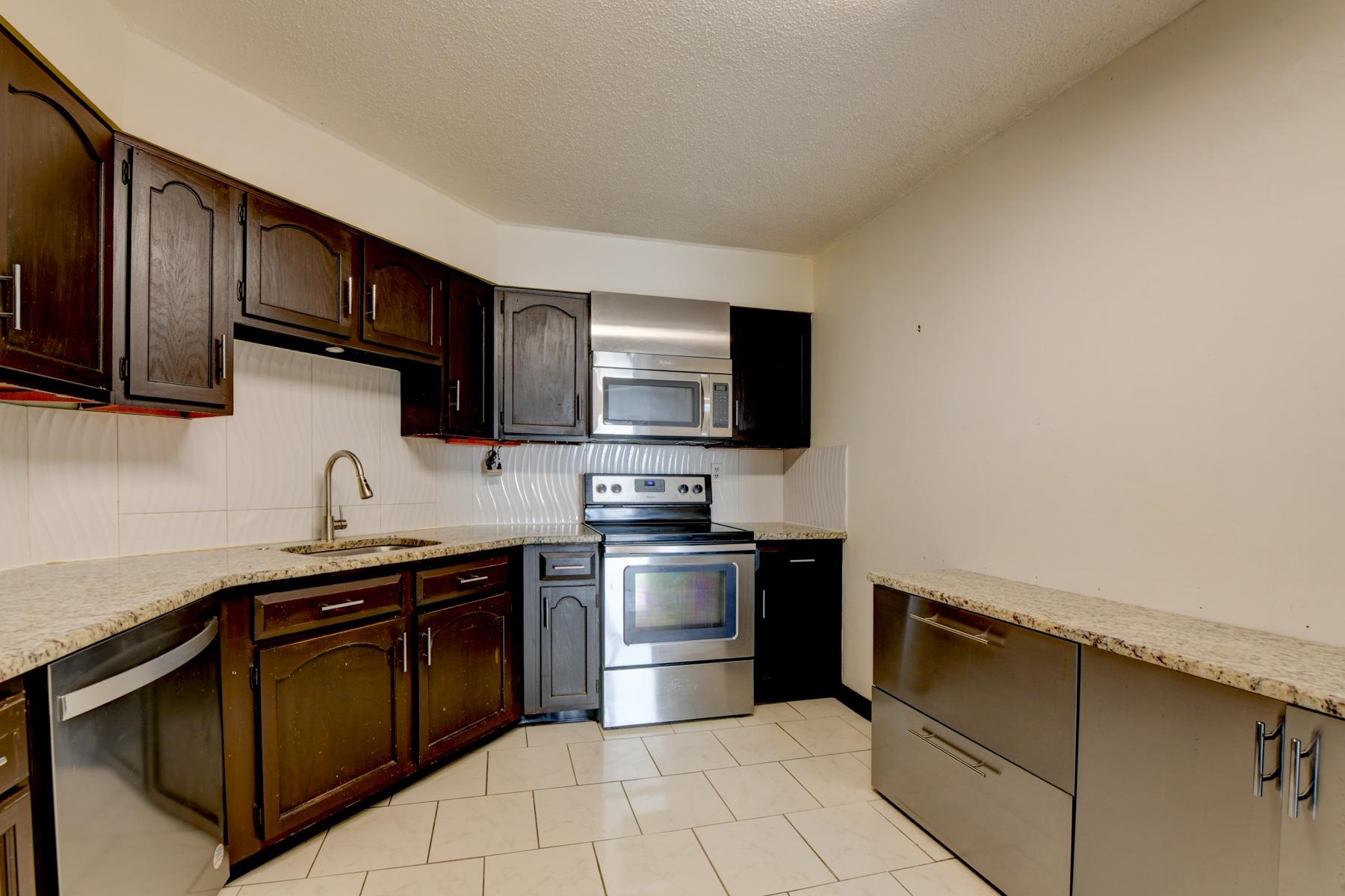 232 Harmon Cove Tower, Unit 232 Secaucus, NJ 07094 - Photo 9 of 47 a kitchen with stainless steel appliances granite countertop a sink and a stove top oven with wooden floor