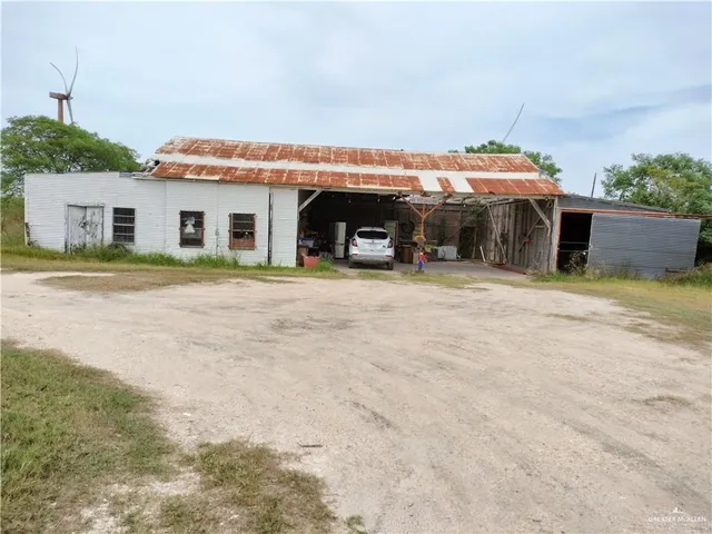 a view of a house with potted plants and a car parked in front of it