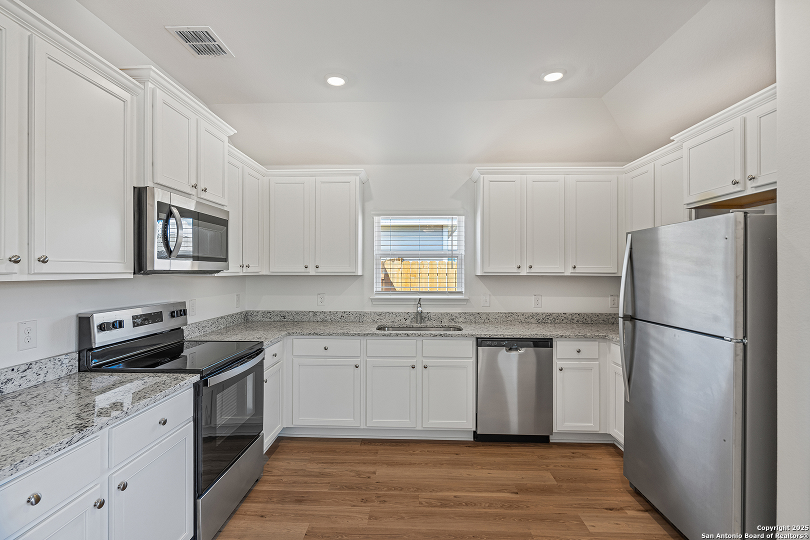 16148 Farmer Lytle, TX 78052 - Photo 9 of 33 a kitchen with granite countertop a refrigerator stove a sink and dishwasher with wooden floor