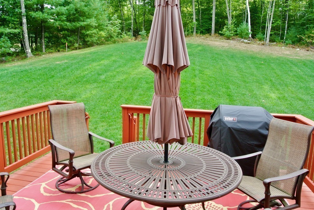 92 Robin Hill Road Groton, MA 01450 - Photo 8 of 30 a view of a deck with a table chairs and a backyard