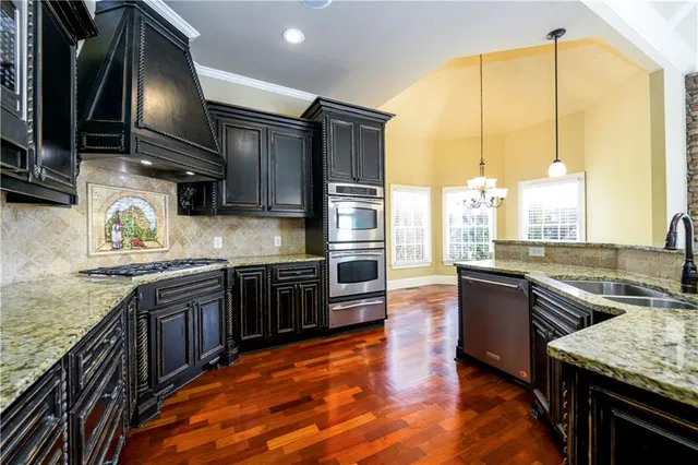 a kitchen with stainless steel appliances granite countertop a stove a sink and a refrigerator