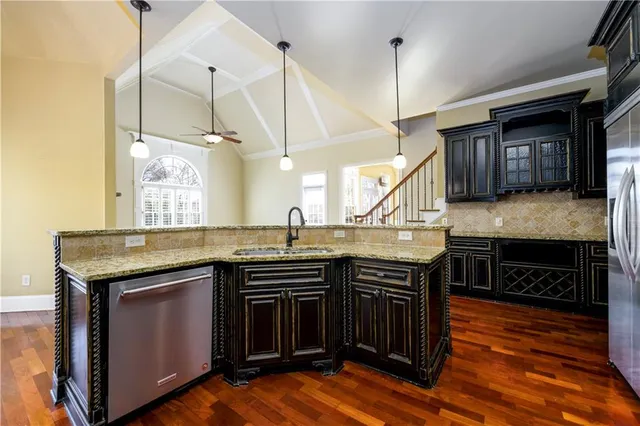 a kitchen with stainless steel appliances granite countertop a stove a sink and a wooden cabinets