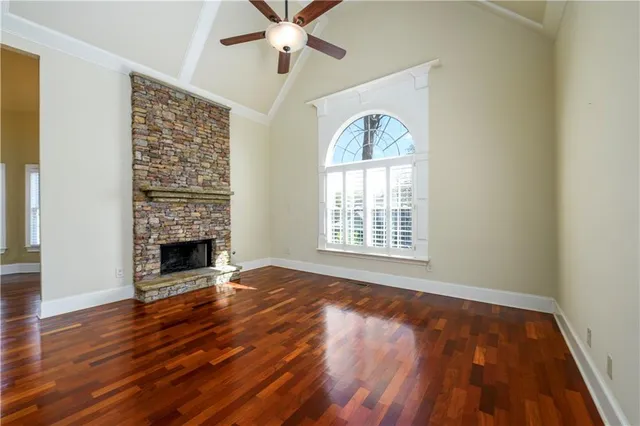 an empty room with wooden floor fireplace and windows