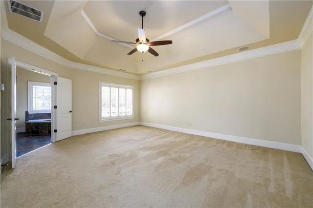 an empty room with chandelier fan and windows
