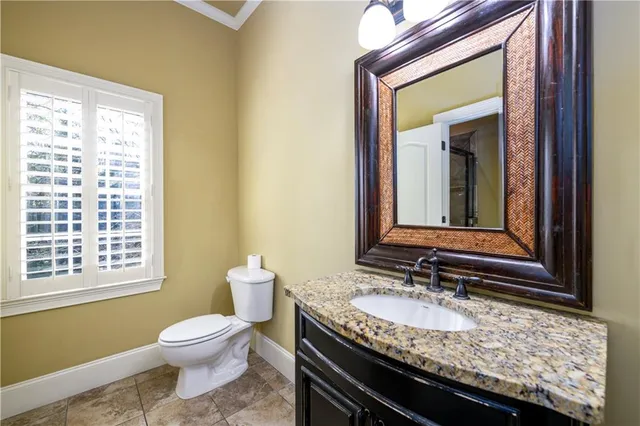 a bathroom with a granite countertop toilet sink and mirror