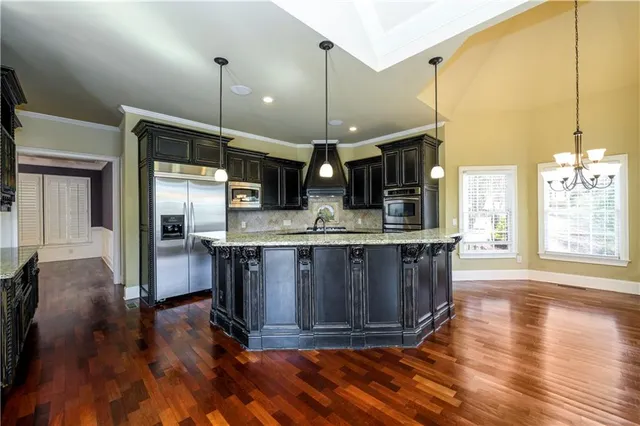 a kitchen with stainless steel appliances granite countertop a stove a sink and a wooden floors