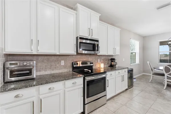 a kitchen with granite countertop white cabinets and stainless steel appliances