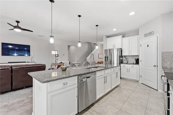 a kitchen with stainless steel appliances granite countertop a sink a stove and a chandelier