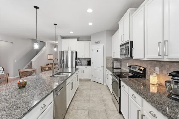 a large kitchen with stainless steel appliances granite countertop a sink a stove and a wooden floor